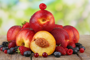 Peaches with berries on table on natural background