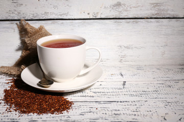 Cup of tasty rooibos tea, on old white wooden table