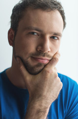 Close-up portrait of attractive young man holding chin.