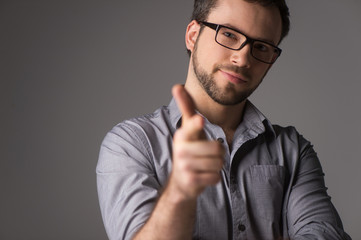 Close-up portrait of attractive young man showing gun sign