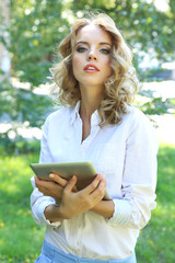 Fototapeta premium Beautiful young girl with tablet on city street