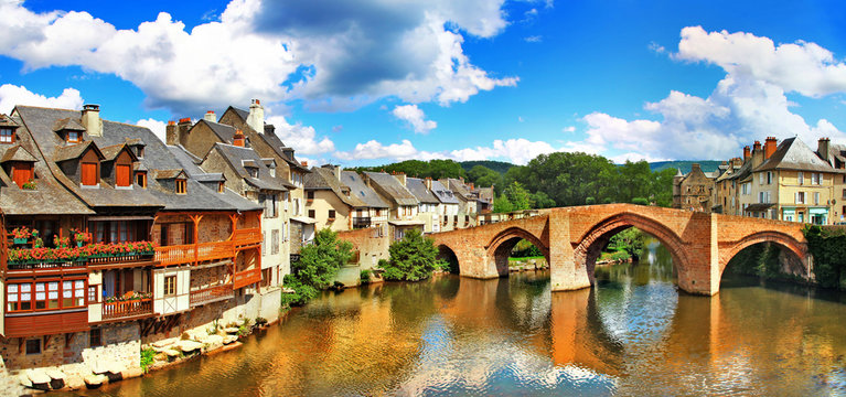 France Espalion medieval river view with arched stone bridge 8K, old houses and wooden balconies reflection no people, Aveyron. One of the most beautiful villages of France