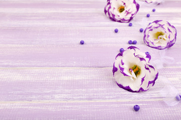 beautiful artificial eustomas on purple wooden background