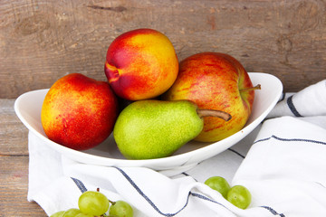 ripe fruits in bowl on wooden background