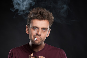 Young man smoking cigarette on black background.