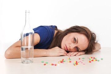 Pills scattered on table with bottle on white background.