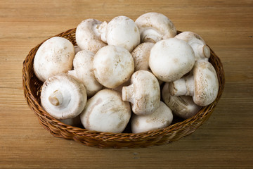 Fresh mushrooms in a basket on a wooden table