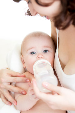 mom feeding by milk her baby infant from bottle
