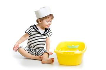 Cute baby boy playing sailor with paper boats