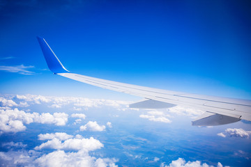 Naklejka premium airplane wing with blue sky and white clouds