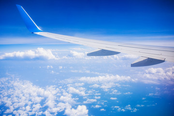Fototapeta na wymiar airplane wing with blue sky and white clouds