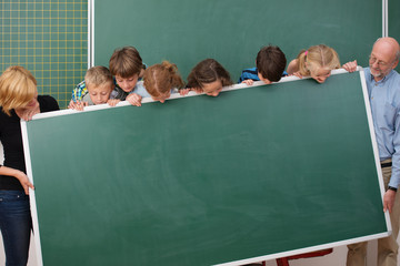 schulkinder und lehrer schauen auf eine tafel