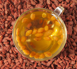 Tea made from goji berries in a glass cup on a background of goj