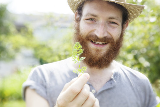 young beauty bearded farmer man holding a little cute leaf