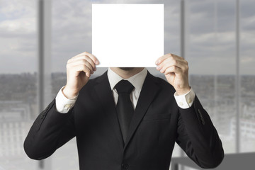 businessman hiding face behind paper