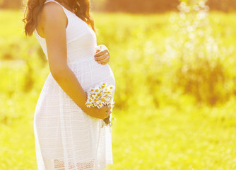Fototapeta na wymiar Pregnancy lovely woman with flowers in summer sunny day, tender