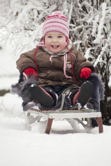 Радостный ребёнок сидит на санках. Снежный фон
