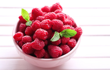 Ripe sweet raspberries in bowl on table close-up