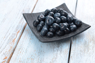 Delicious blueberries on plate on table close-up