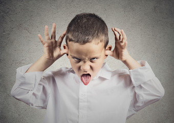 Unhappy, bully child, making faces, sticking out his tongue