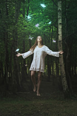 Beautiful woman levitation in a dark forest