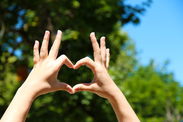 Young girl holding hands in heart shape framing