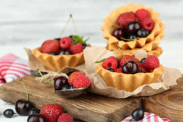 Tasty tartlets with berries on wooden table