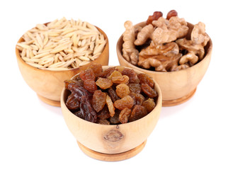 Small wooden bowls with raisins, walnuts and oats isolated