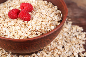 Big brown bowl with oatmeal and berries on a wooden table