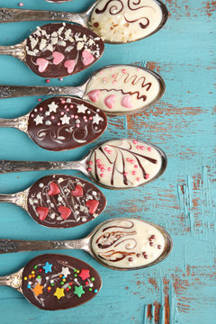 Spoons with tasty chocolate for party on old blue wooden table