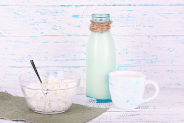 Glass bottle of milk and cottage cheese on wooden background
