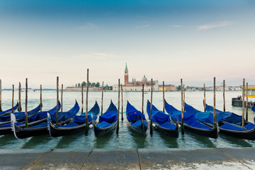 Fototapeta na wymiar Gondolas moored by Saint Mark square with San Giorgio di Maggior
