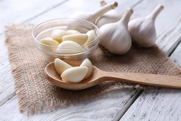 Gordijnen Fresh sliced garlic in glass bowl on wooden background © Africa Studio