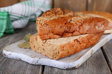 Fresh baked bread on cutting board, on wooden background
