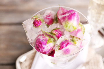 Obraz na płótnie Canvas Ice cubes with rose flowers in glass bowl and two glasses with