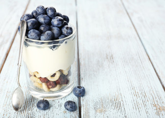 Natural yogurt with fresh blueberries on wooden table