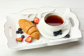 Delicious breakfast with cup of tea, fresh croissant and