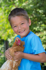 Lachender Junge mit Huhn auf dem Arm