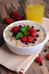Tasty oatmeal with berries on table close-up