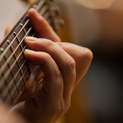 The hand of man playing guitar closeup