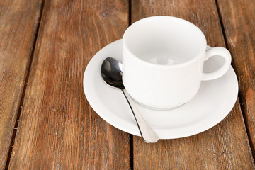Empty cup with tea spoon on wooden background