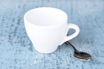 Empty cup with tea spoon on wooden background