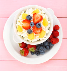 Cottage cheese with fruits and berries in bowl on wooden table