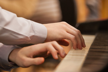 Children's hands on the keyboard of the piano