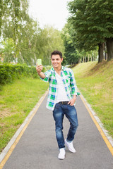 Fototapeta premium Handsome young hipster man taking a selfie in park