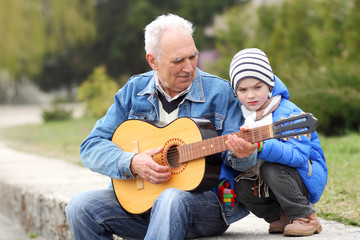 Grandfather and grandson draw with chalk on the road