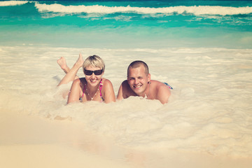 Young romantic couple laying on sandy beach