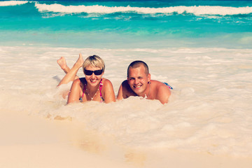 Fototapeta premium Young romantic couple laying on sandy beach