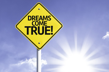 Dreams Come True! road sign with sun background