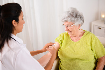 cheerful elderly woman receiving injection from a young nurse